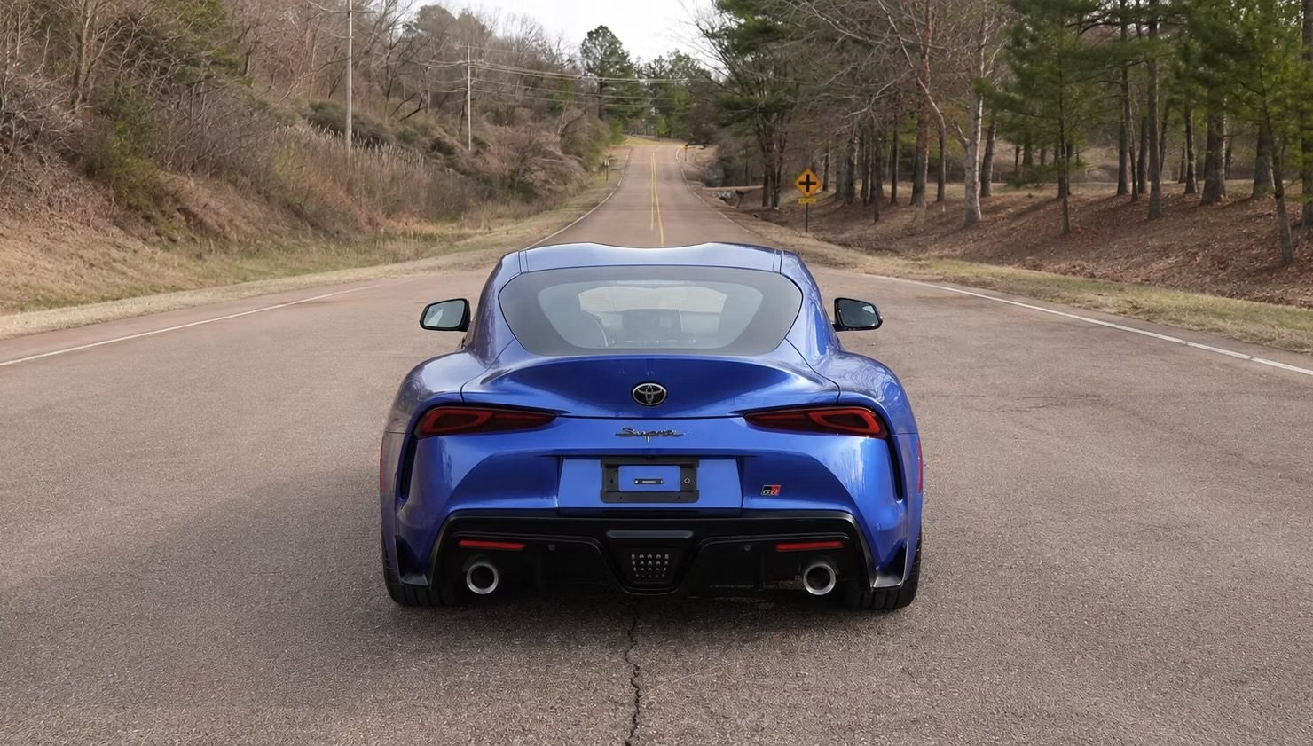 Detailed blue Toyota Supra, rear view on a country road